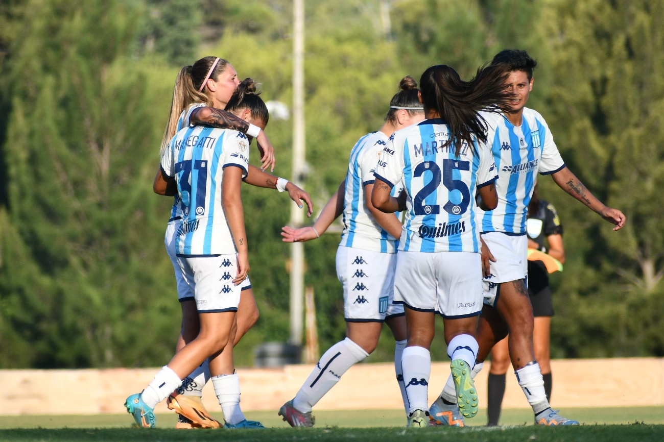 Un grupo de mujeres jugando fútbol en el pasto Descripción generada automáticamente