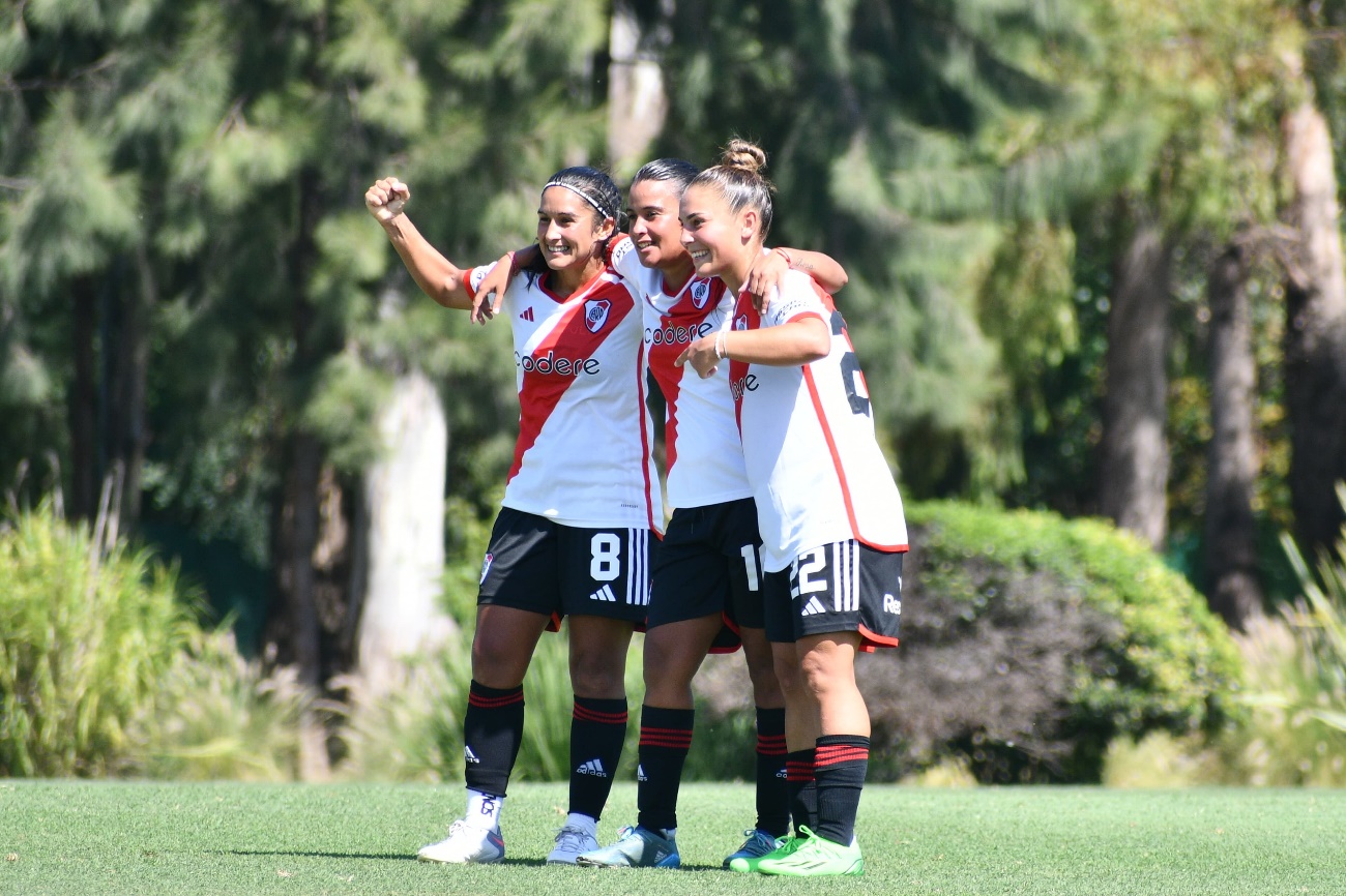 Un par de mujeres jugando fútbol en el pasto Descripción generada automáticamente con confianza media